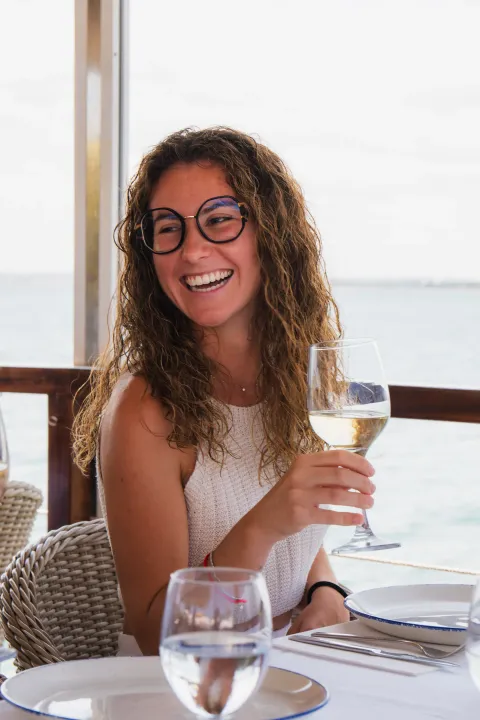 Clienta con gafas de sol brindando con vino blanco